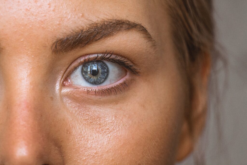 Close-up of a person's eye revealing detailed eyelashes, eyebrow, and blue iris.